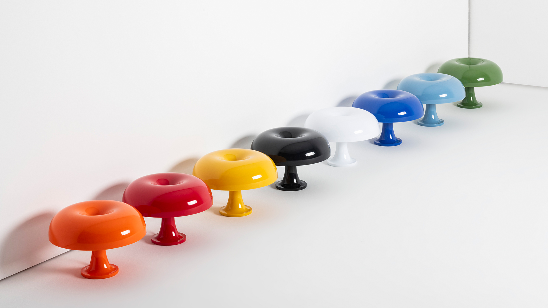 Eight glossy donut-shaped Nessino table lamps by Artemide in various colors: yellow, orange, red, white, black, blue, light blue, and green