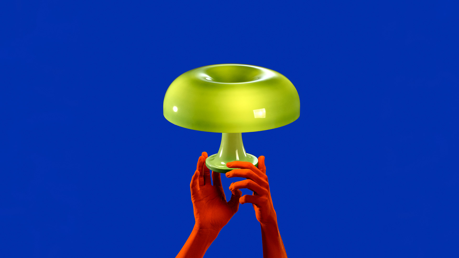 Two Artemide Nessino table lamps with mushroom-shaped shades: orange on the left, red on the right, on a white surface