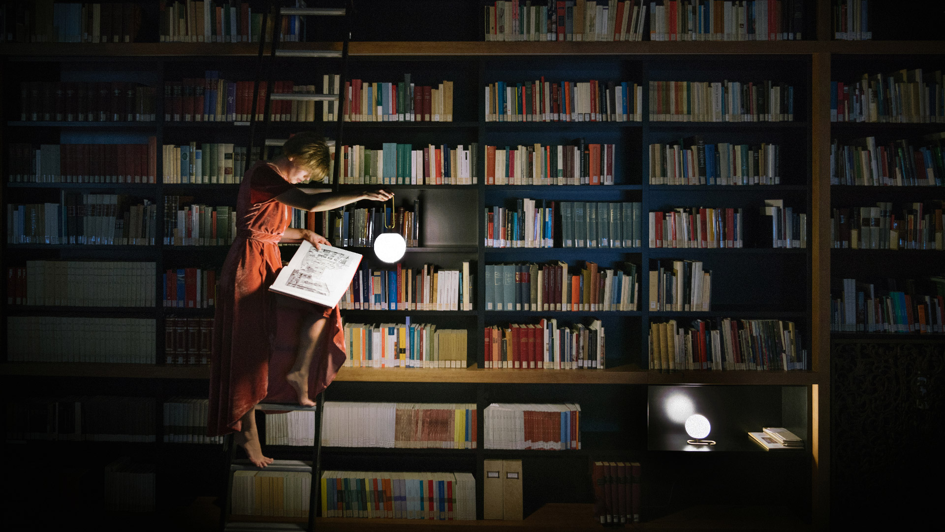 Artemide NH table and wall lamps with opal glass spheres and brass details on a wooden dresser with books and flowers