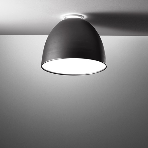 Artemide Nur Mini ceiling lamp with dark brushed dome shade, mounted flush to ceiling, emitting soft downward light