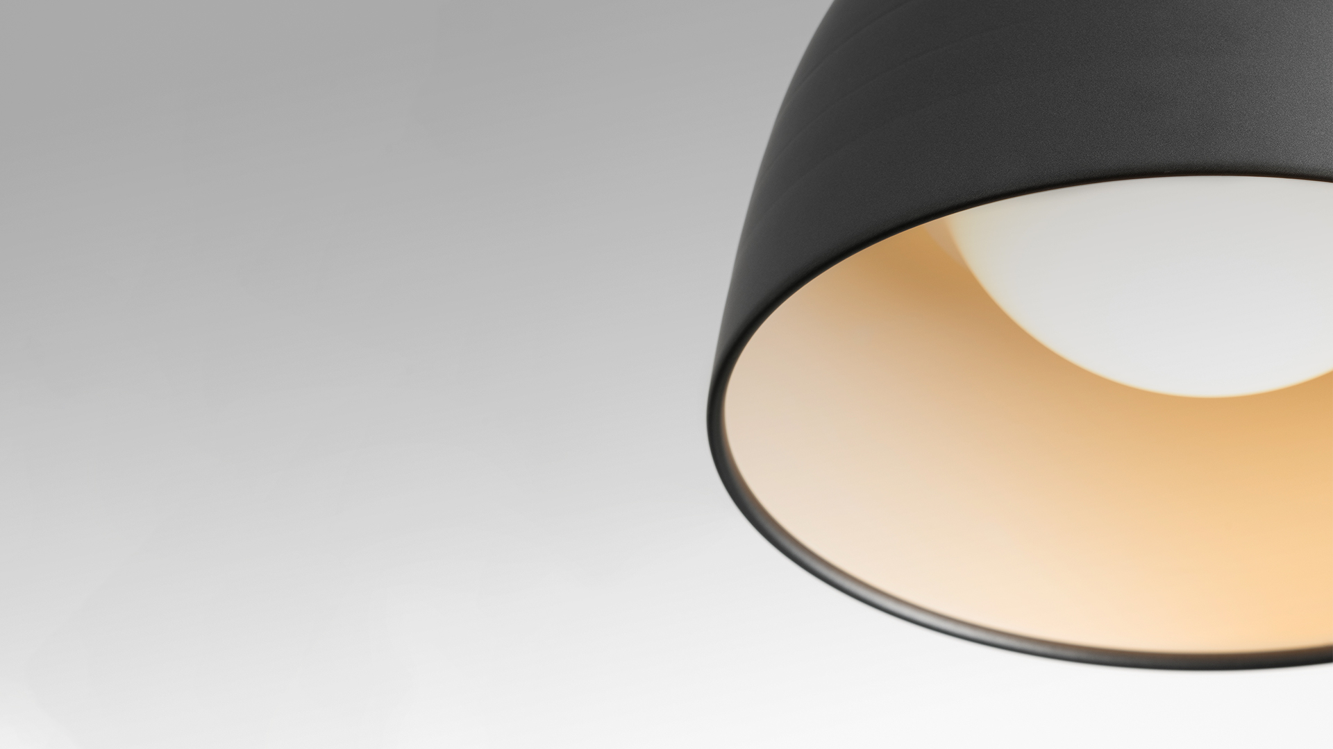 Artemide Nur pendant lamp with large aluminum dome shade in grey finish, emitting warm downward light, suspended by white cables