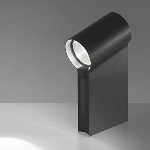Artemide Oblique table spotlight in matte black, cylindrical rotating head on rectangular base, projecting focused beam downward