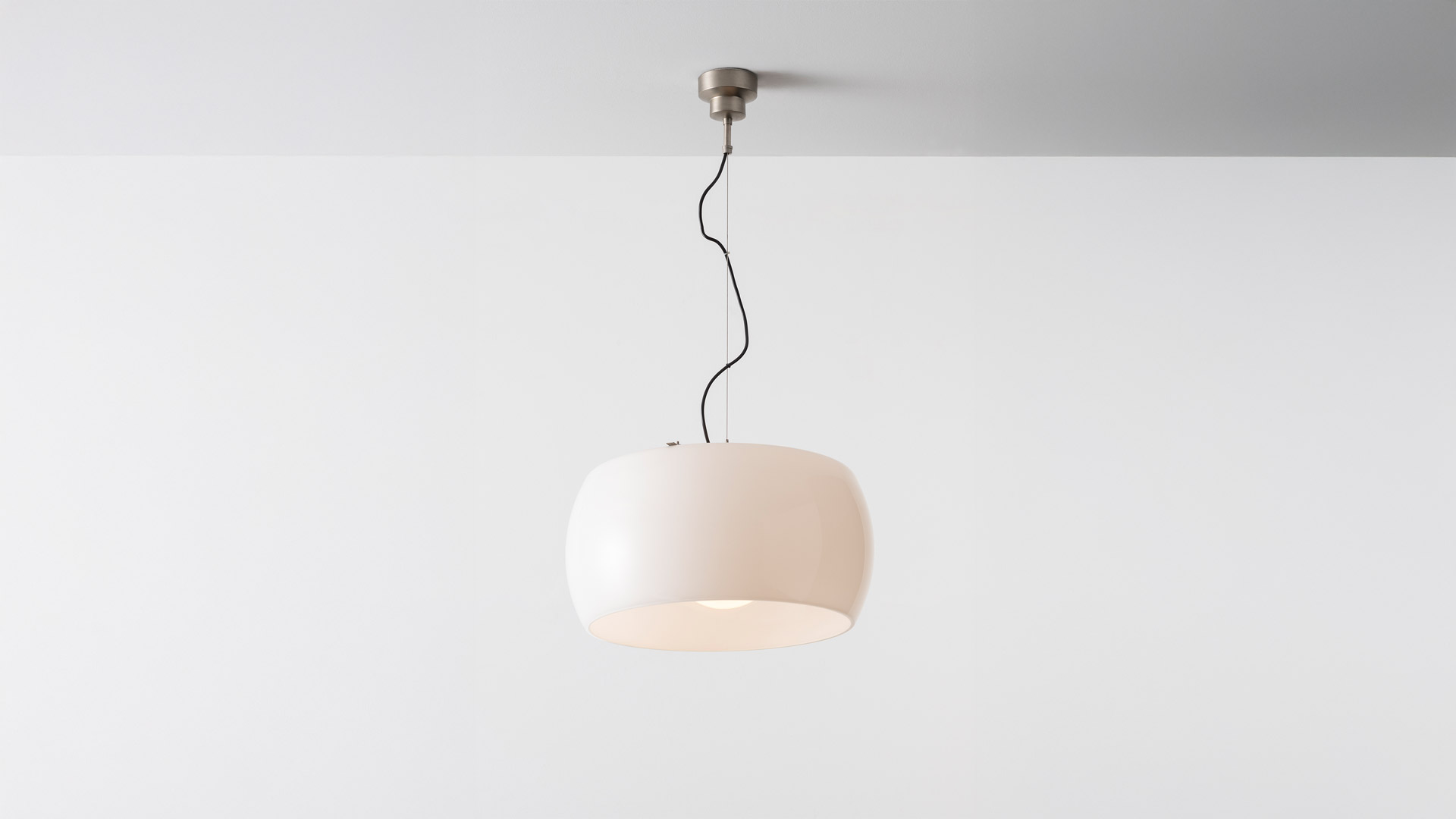 Close-up of Artemide Omega pendant lamp, dome-shaped shade in warm beige finish with soft glowing interior light