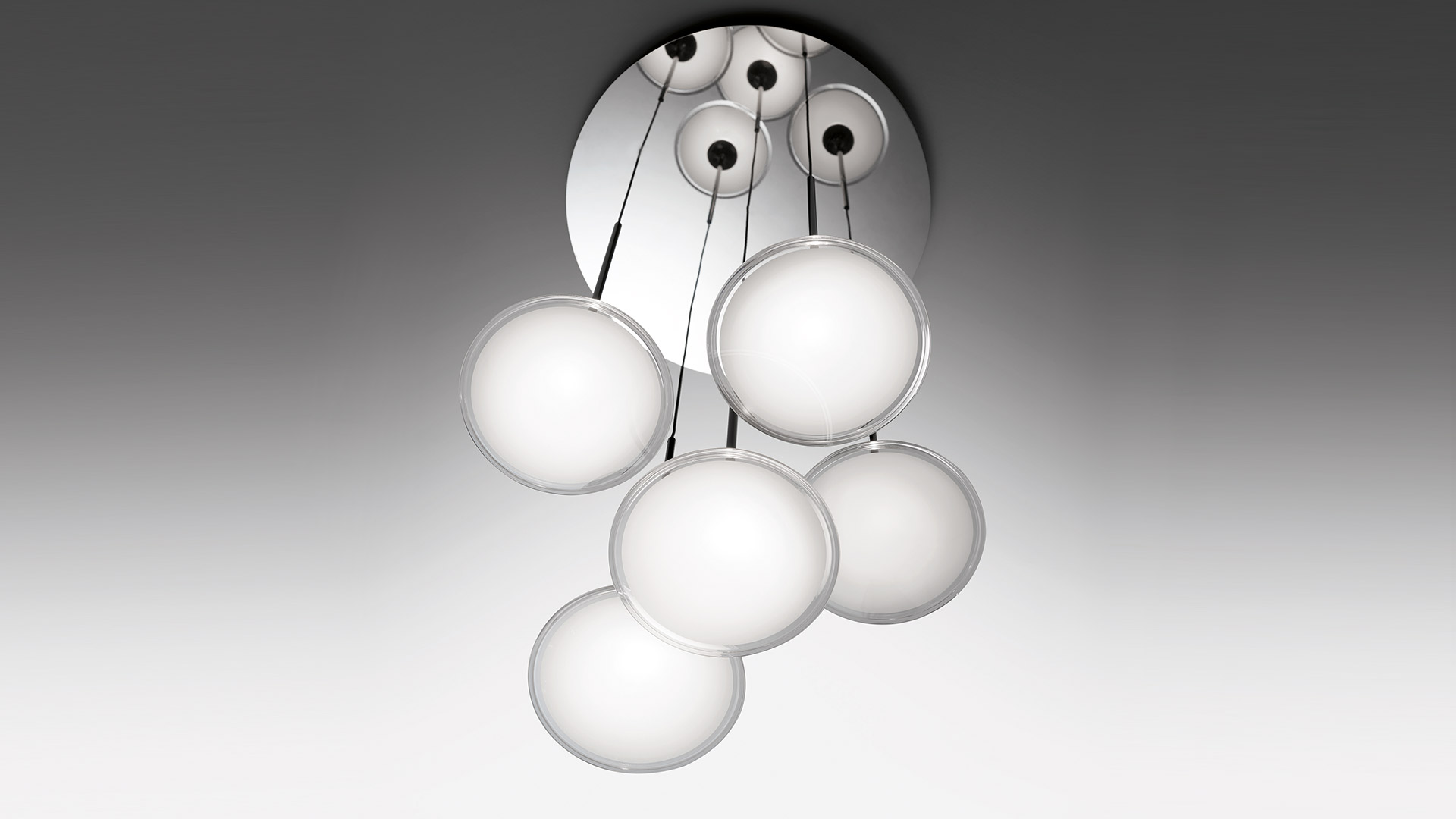 Artemide Orsa Cluster ceiling lamp: six opal white spherical diffusers suspended at varying heights from a circular chrome canopy
