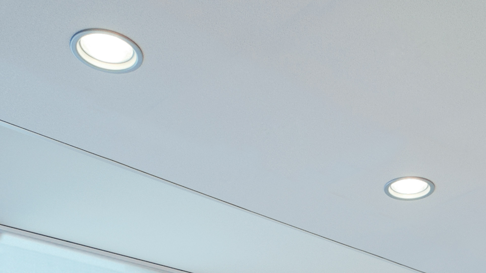 Two Artemide Parabola 100 recessed ceiling spotlights with round trim, emitting warm white light on a clean white ceiling
