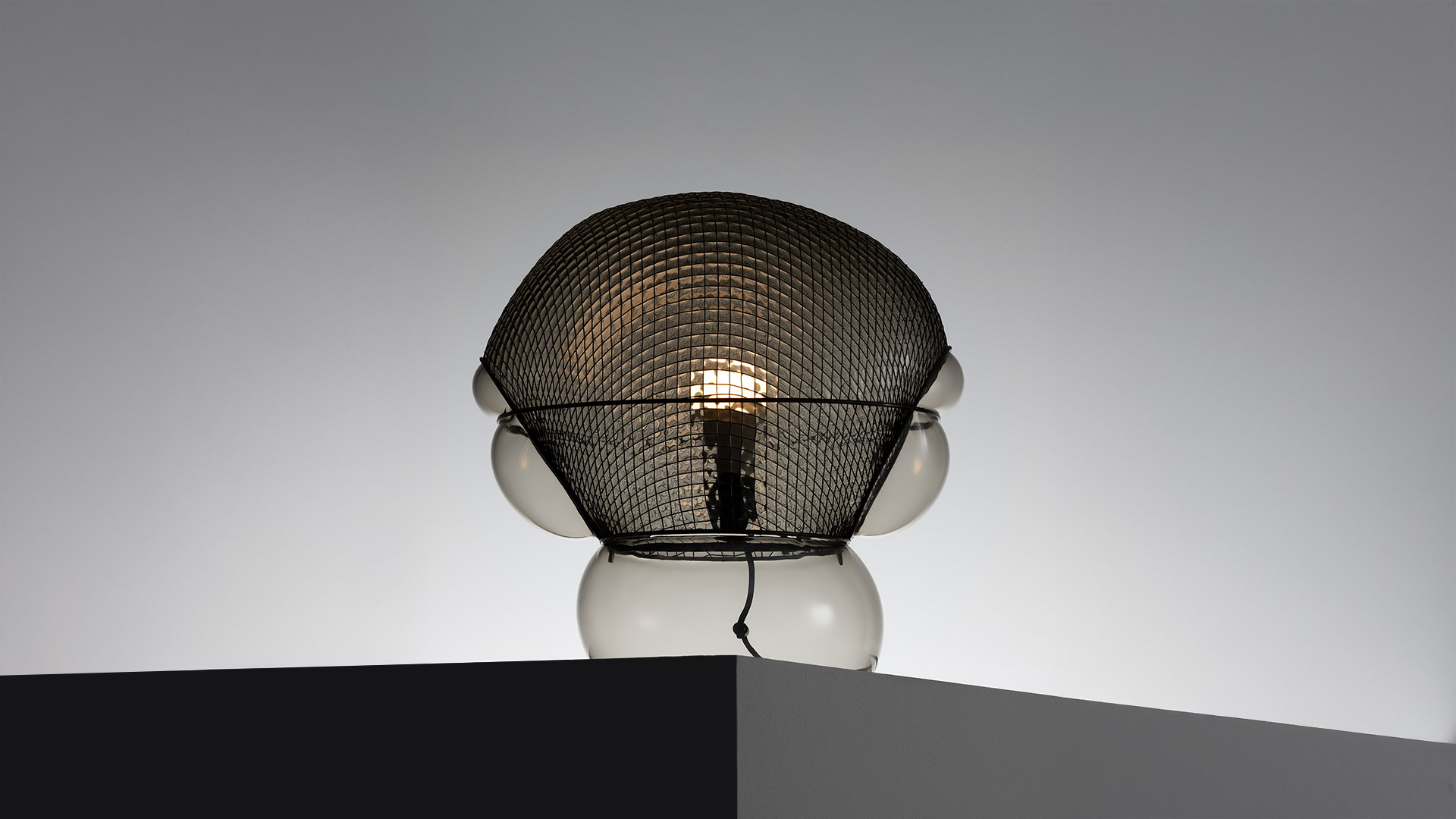 Artemide Patroclo lamp detail: metallic woven mesh shade with diamond pattern wrapping a polished chrome spherical diffuser