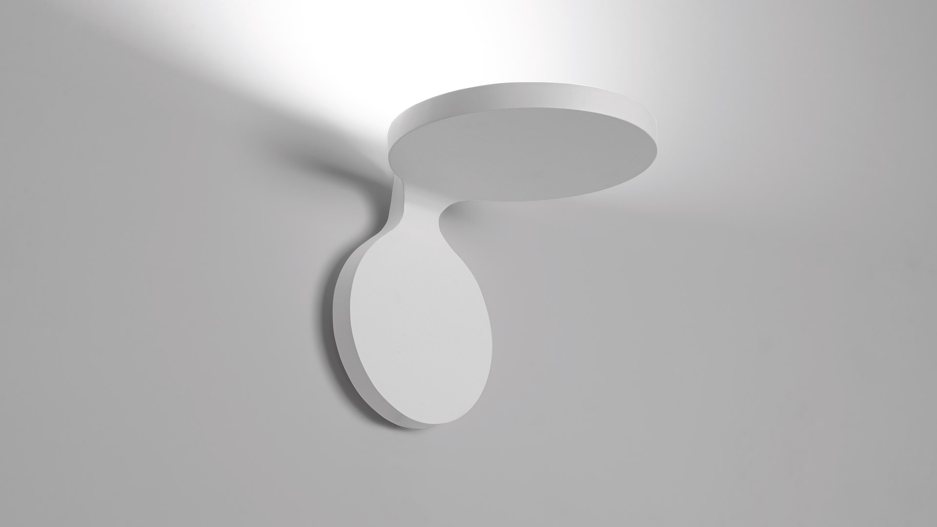 Artemide Rea ceiling lamp: white oval body with circular ceiling plate, emitting soft upward indirect light