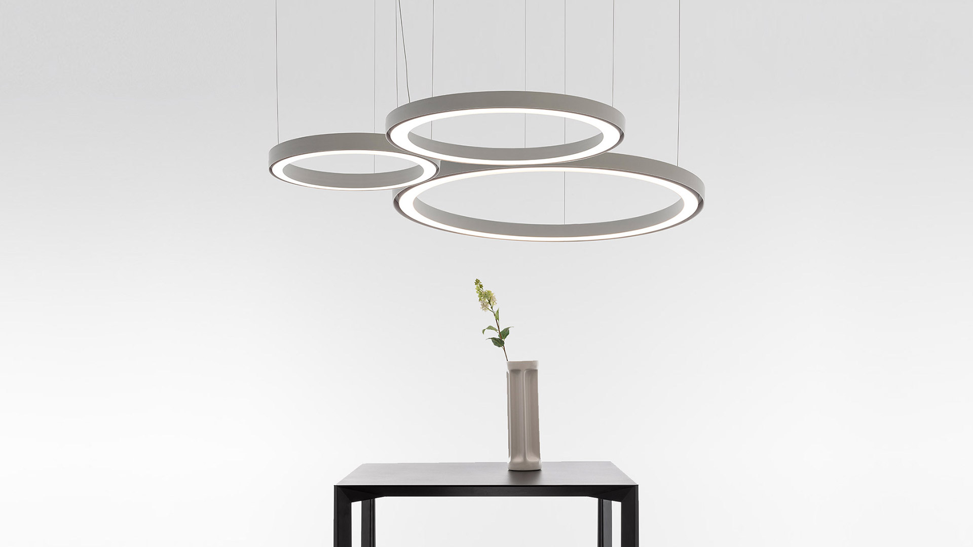 Artemide Ripple ceiling lamp: multiple overlapping luminous rings in glossy black finish emitting bright white LED light against dark background