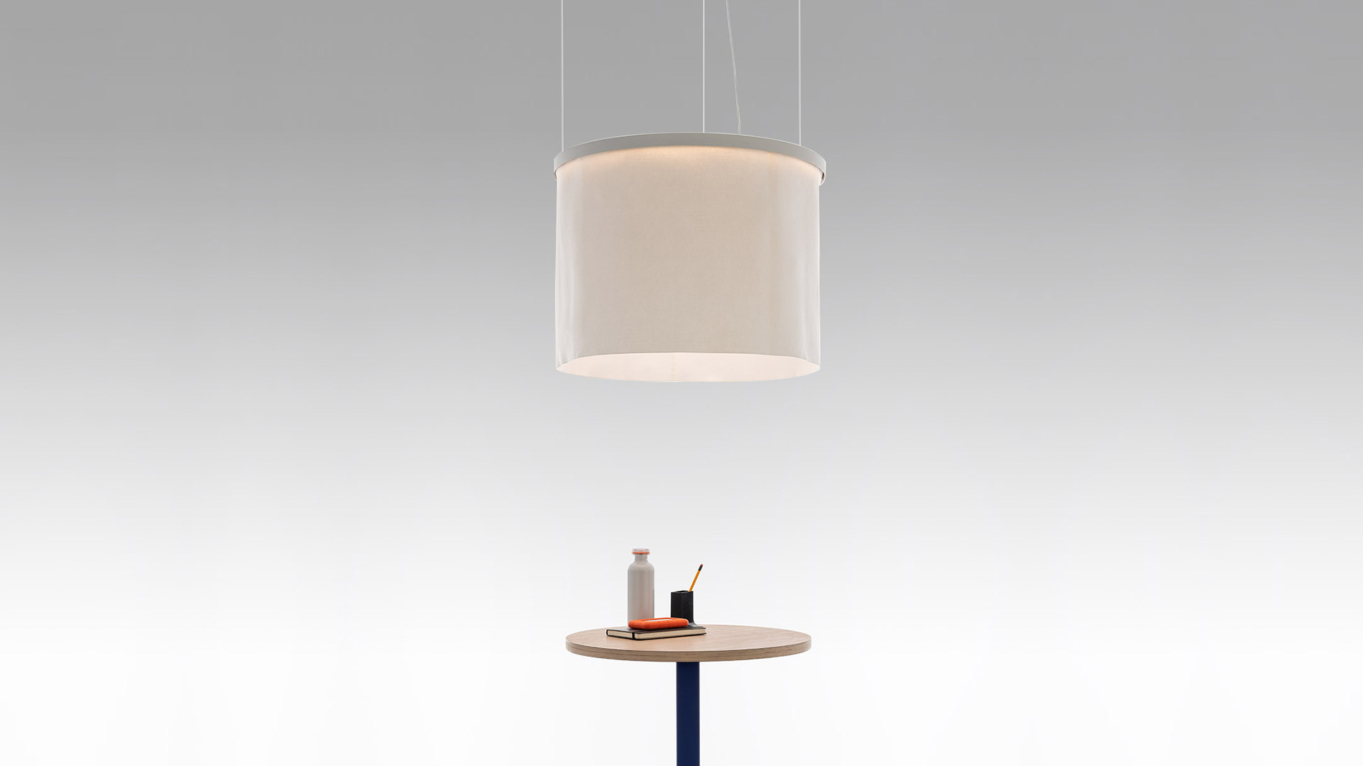 Three Artemide Ripple pendant lamps with cylindrical fabric shades in warm grey, arranged in a cascading cluster emitting soft diffused light
