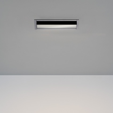 Artemide Sharp Wallwasher recessed ceiling light with slim rectangular black and chrome frame emitting a soft horizontal beam