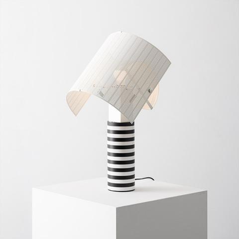 Artemide Shogun table lamp with black-and-white striped cylindrical base and tilted semi-cylindrical ribbed white shade