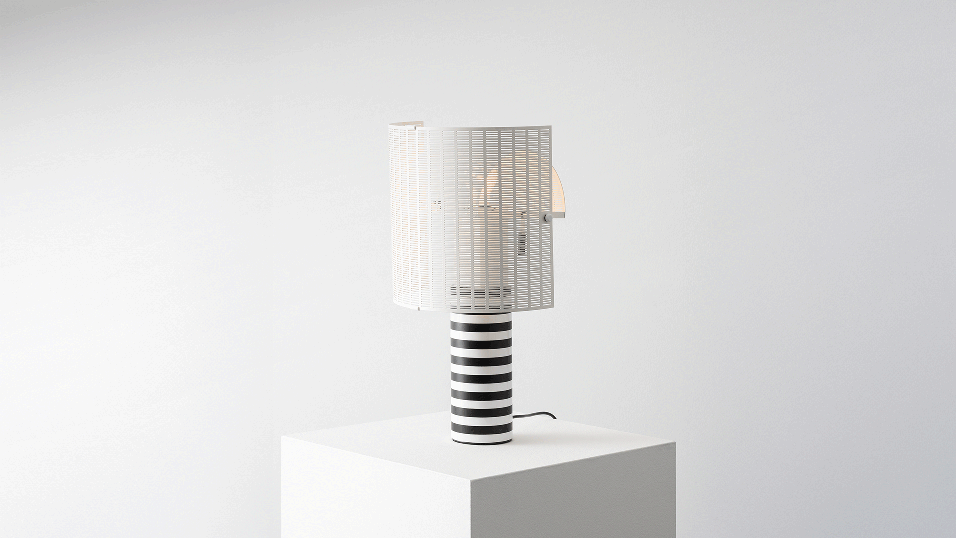 Artemide Shogun table lamp detail: cylindrical base with bold black and white horizontal stripes and white slatted diffuser shade