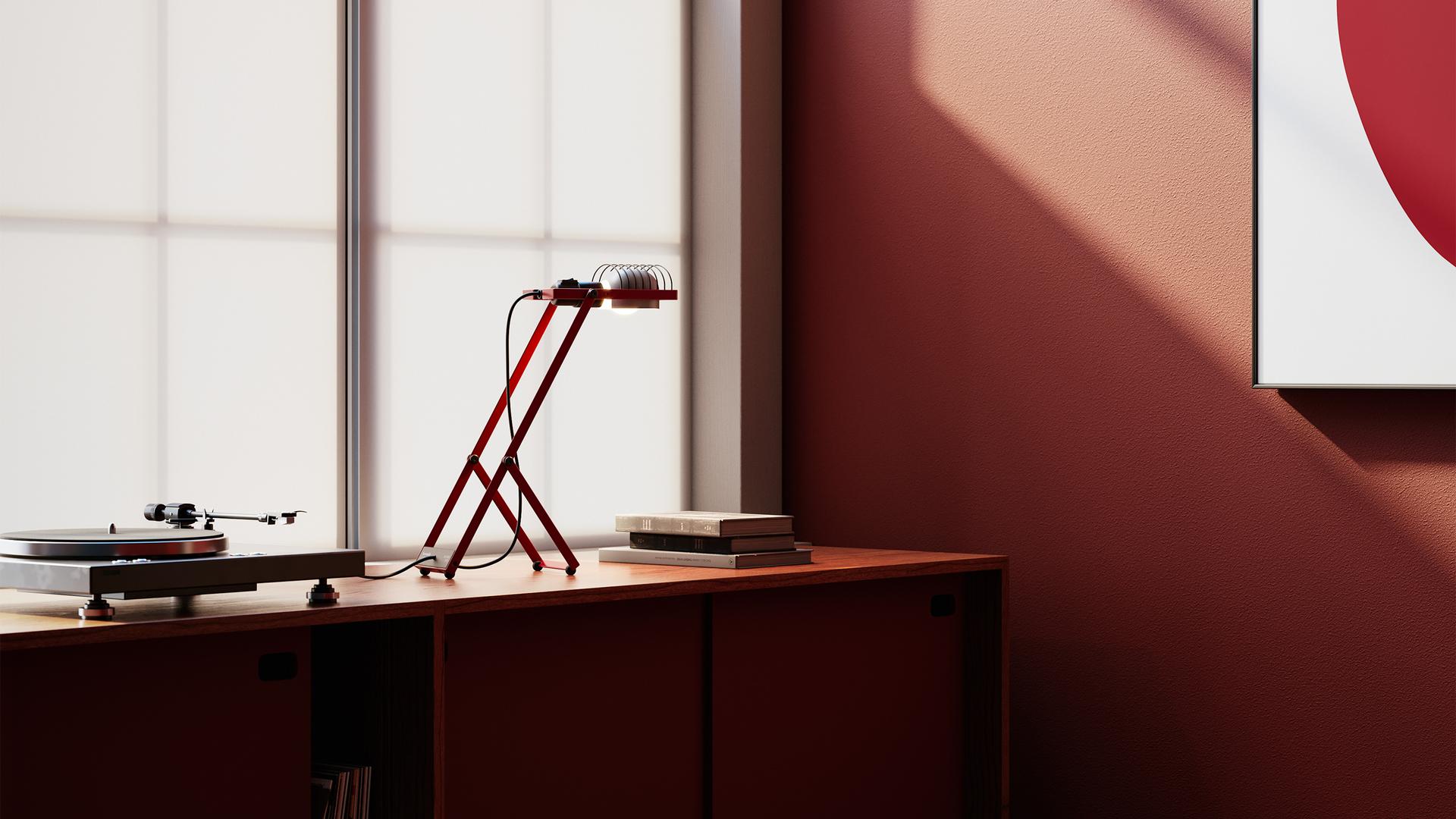 Artemide Sintesi red desk lamp with angular metal frame, illuminating an open book against a green background