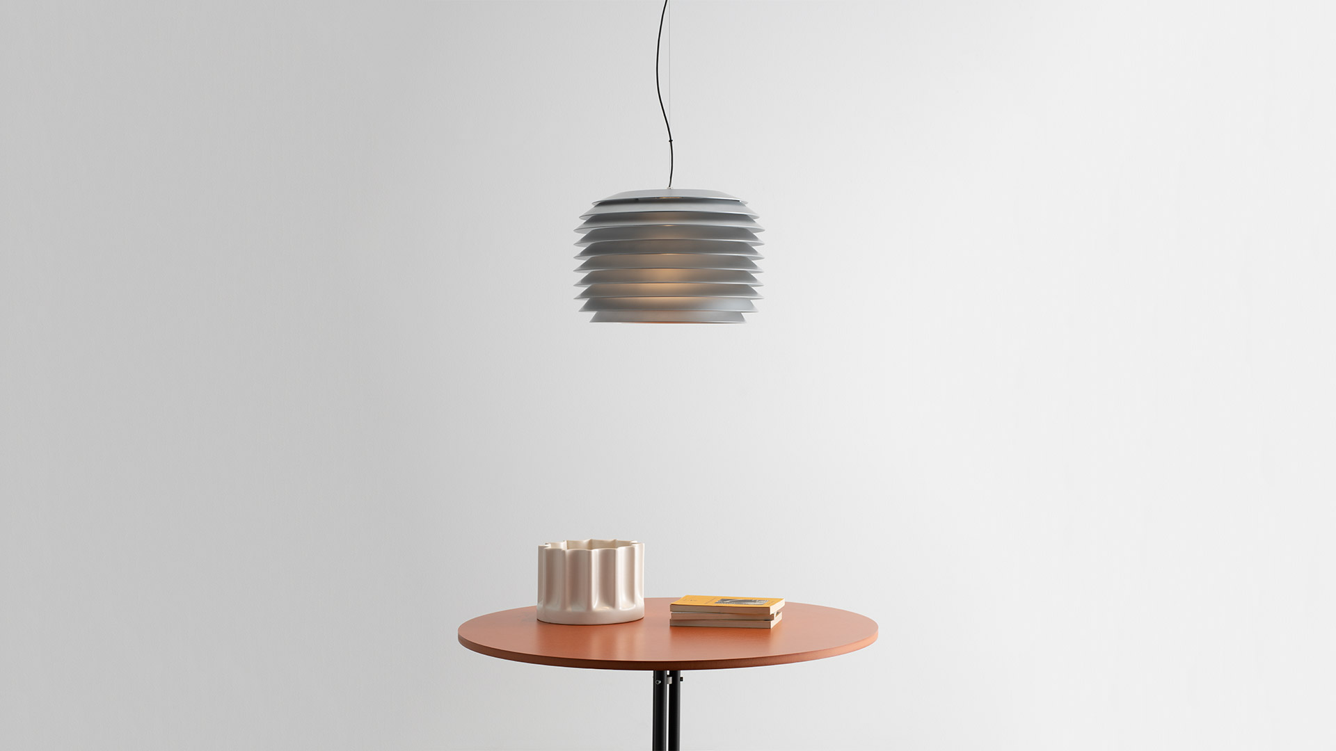 Artemide Slicing outdoor lamps: ribbed cylindrical pendants and bollard lights among ornamental grasses against wooden slat backdrop