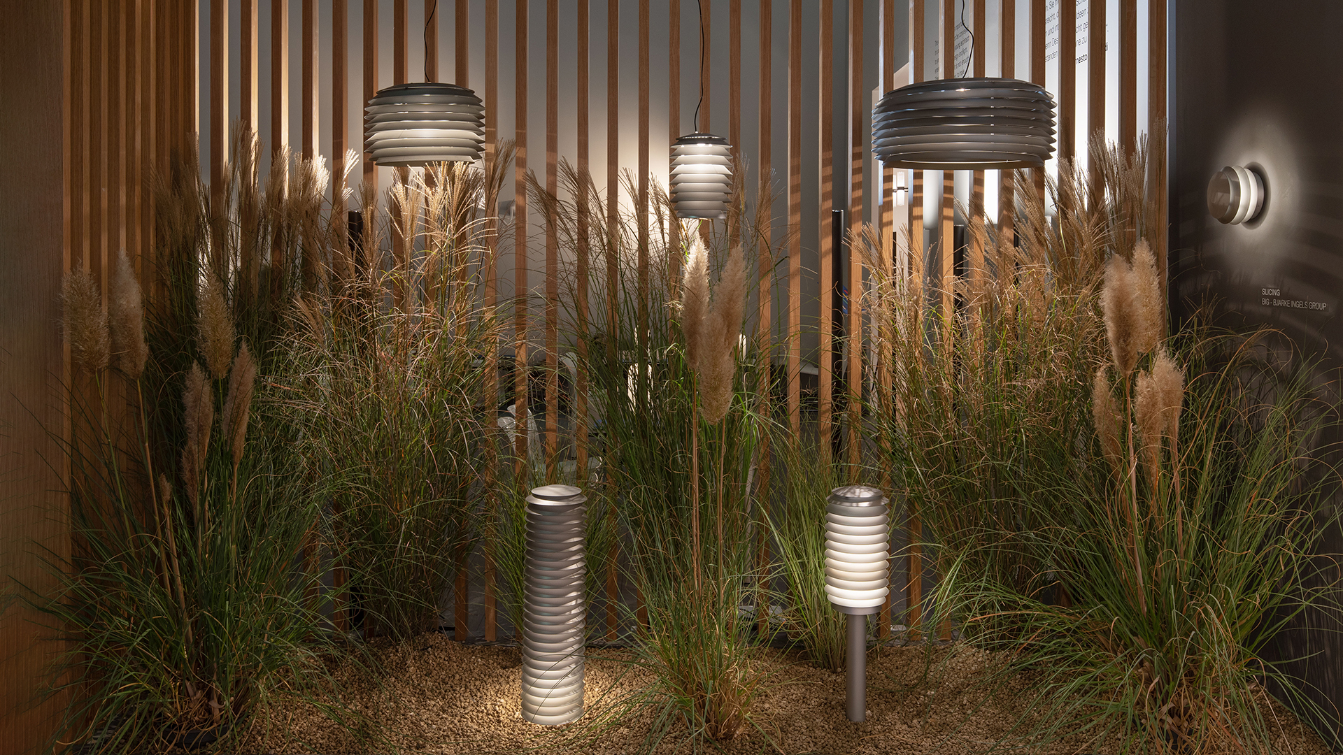 Artemide Slicing pendant lamp with layered cylindrical diffuser glowing warmly outdoors at dusk, suspended against a twilight sky