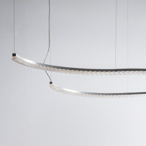Somnĭum System by Artemide: two curved LED pendant lights with crystal optical lenses, suspended at different heights on thin cables