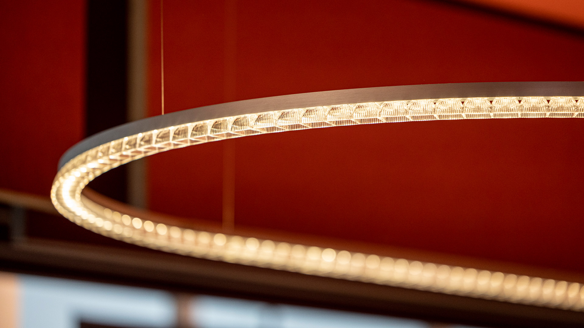 Artemide Somnĭum System pendant lamp: sinuous S-shaped LED light strip suspended by thin cables against a grey background