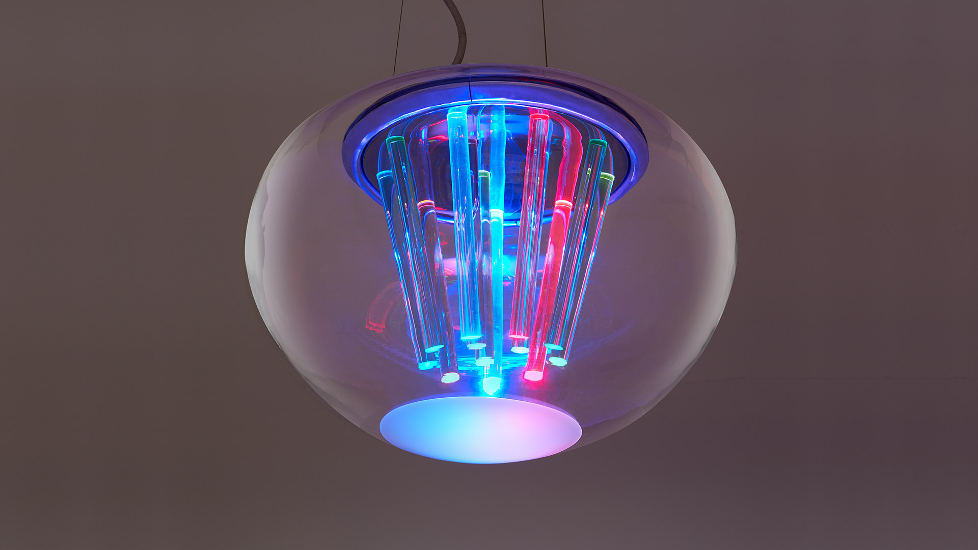Artemide Spectral Light pendant lamp: spherical glass globe enclosing multicolored RGB light tubes emitting blue, red, and green glow