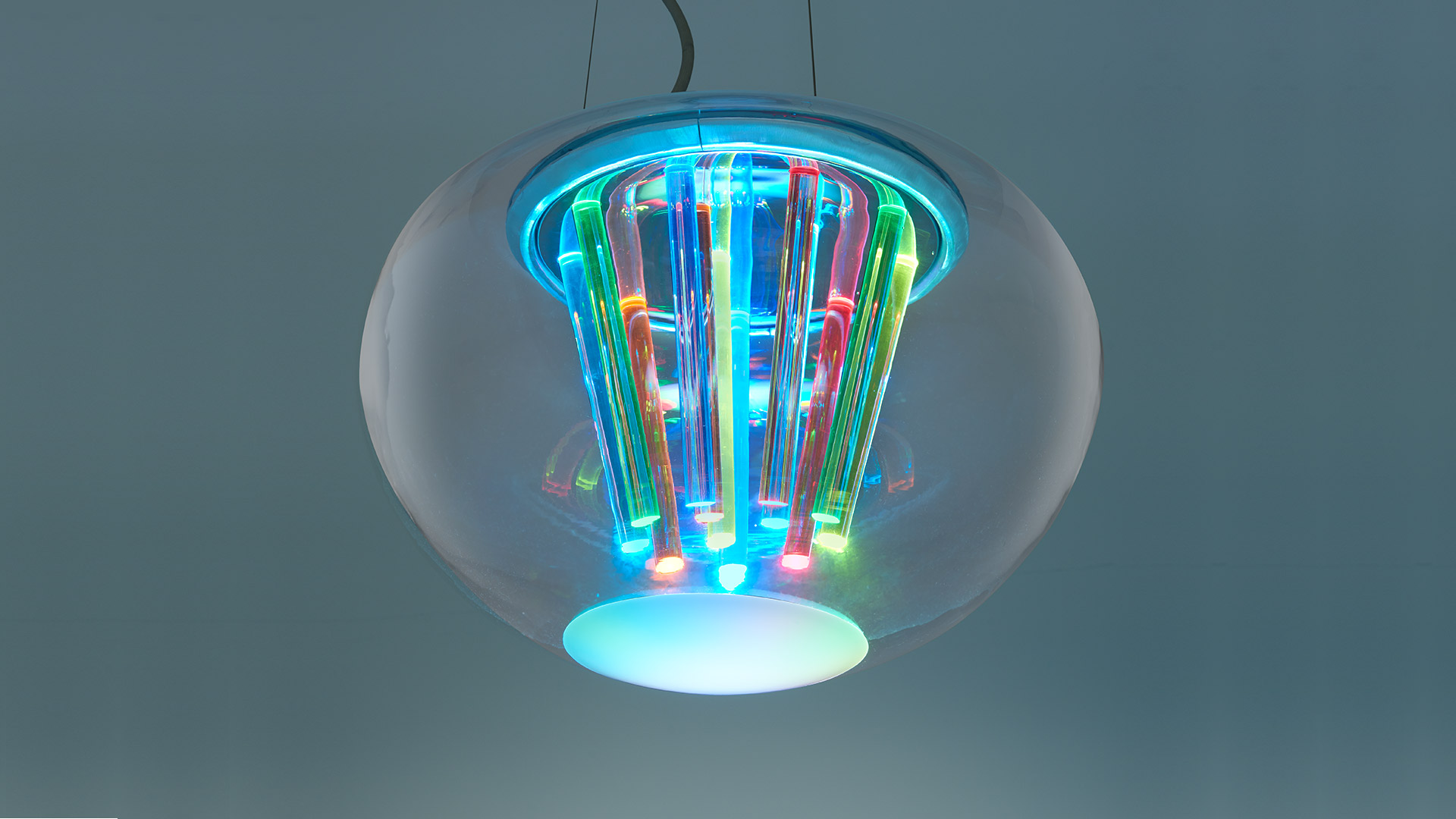 Artemide Spectral Light pendant lamp: transparent glass globe enclosing multicolored LED tubes with cyan and RGB lighting effects