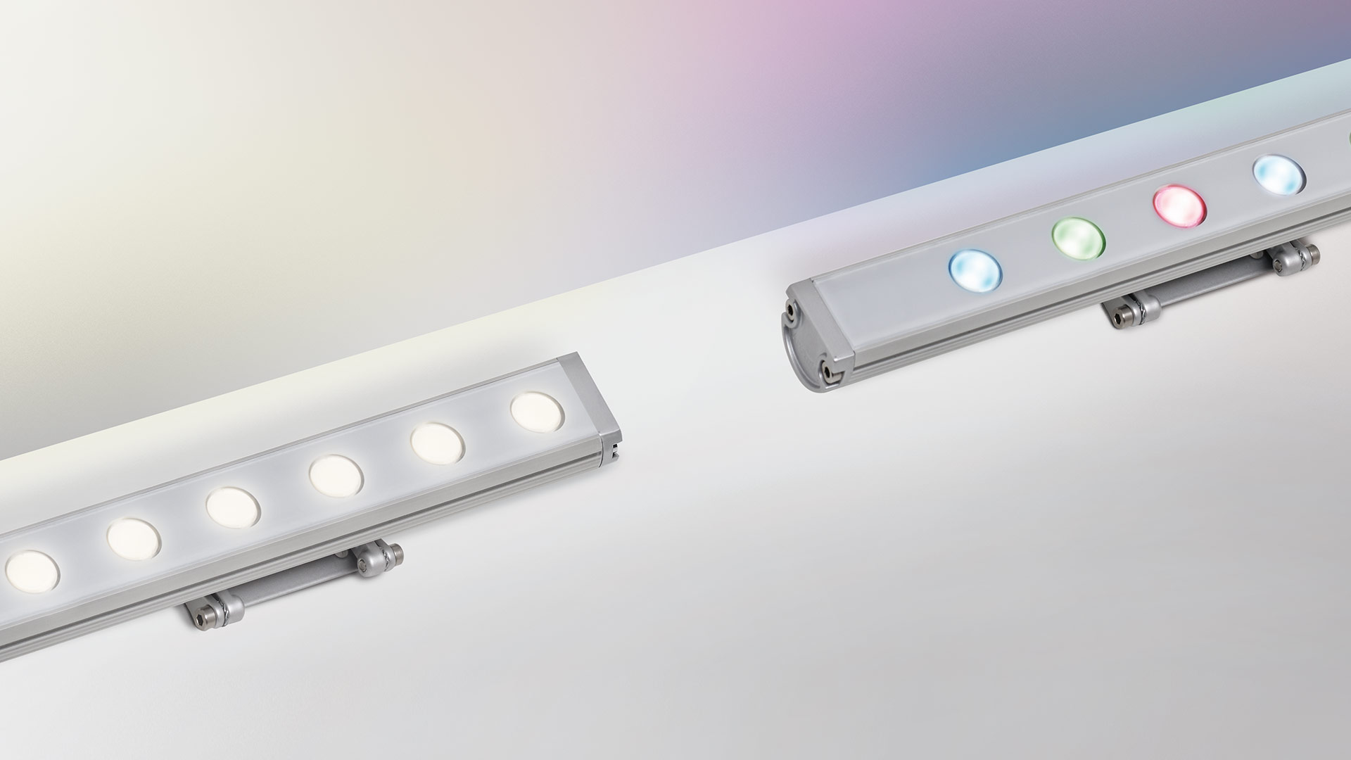 Two Artemide Spike LED wall washers: left emitting white light, right displaying RGB multicolor blue, green, and red LEDs