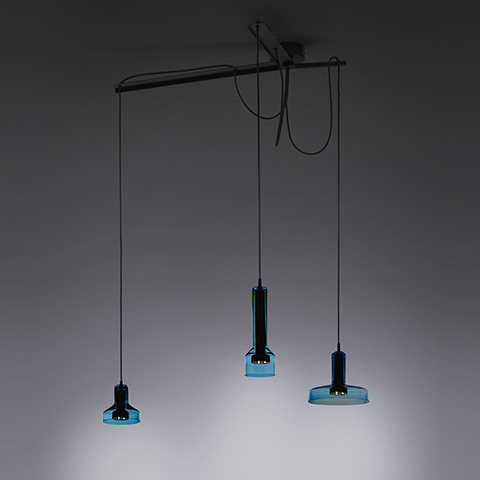 Artemide Stablight: three blue glass pendant lamps at varying heights on black cords, suspended from a horizontal ceiling bar