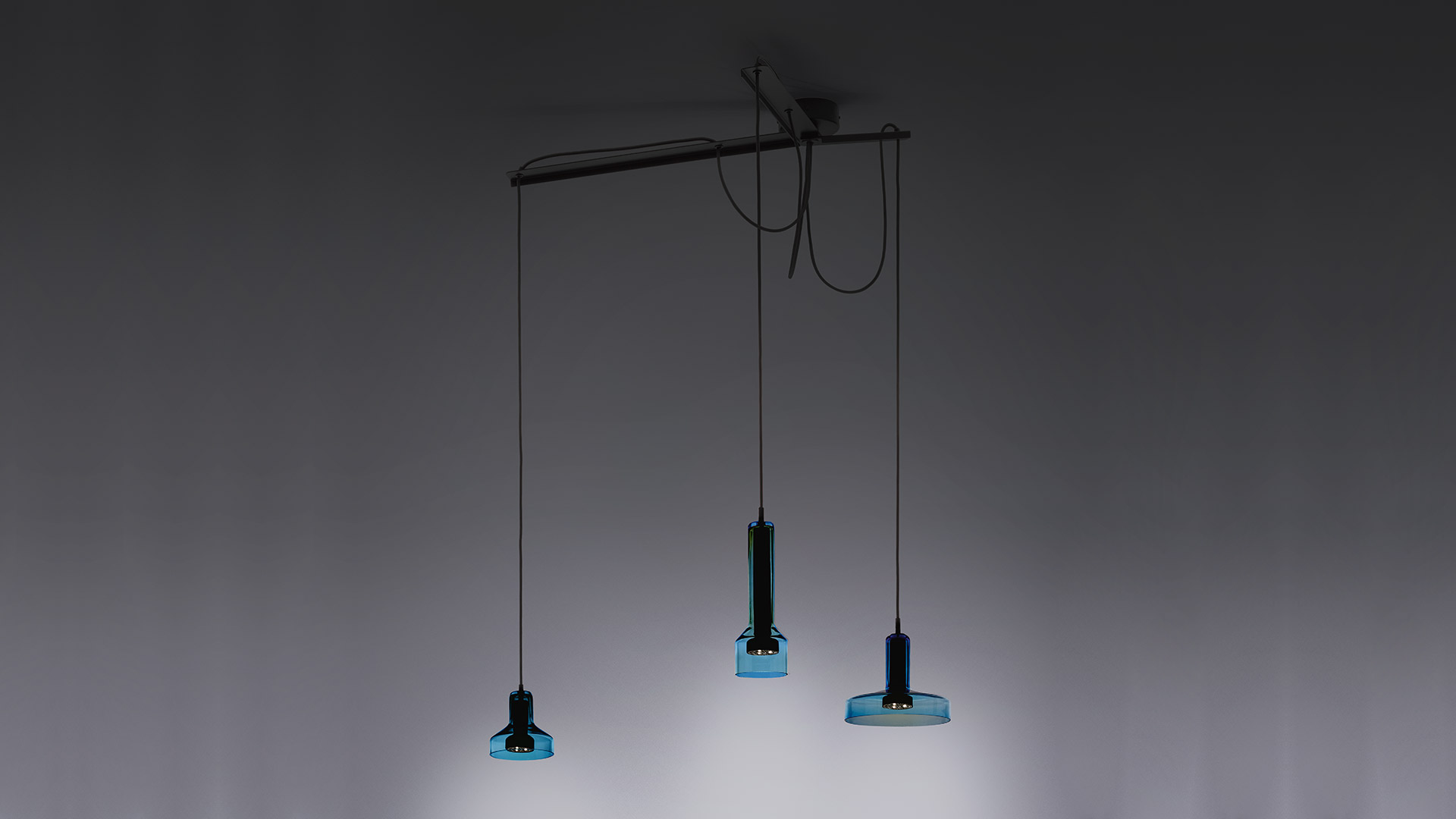 Three Artemide Stablight pendant lamps in gold, blue, and bronze, featuring cylindrical glass bodies with square bases, hanging on black cords