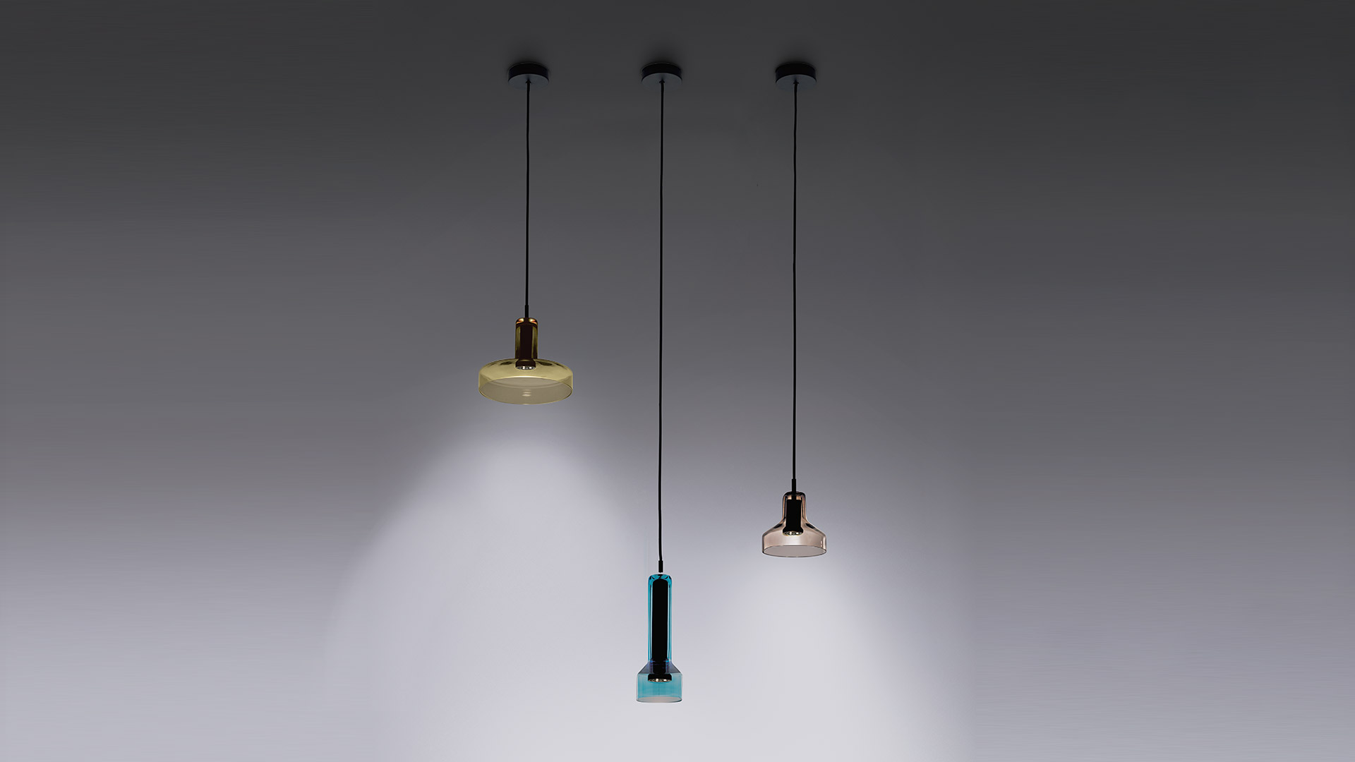 Three Artemide Stablight pendant lamps on black cords: left wide flat amber glass shade, center teal rectangular body, right small amber bell shade