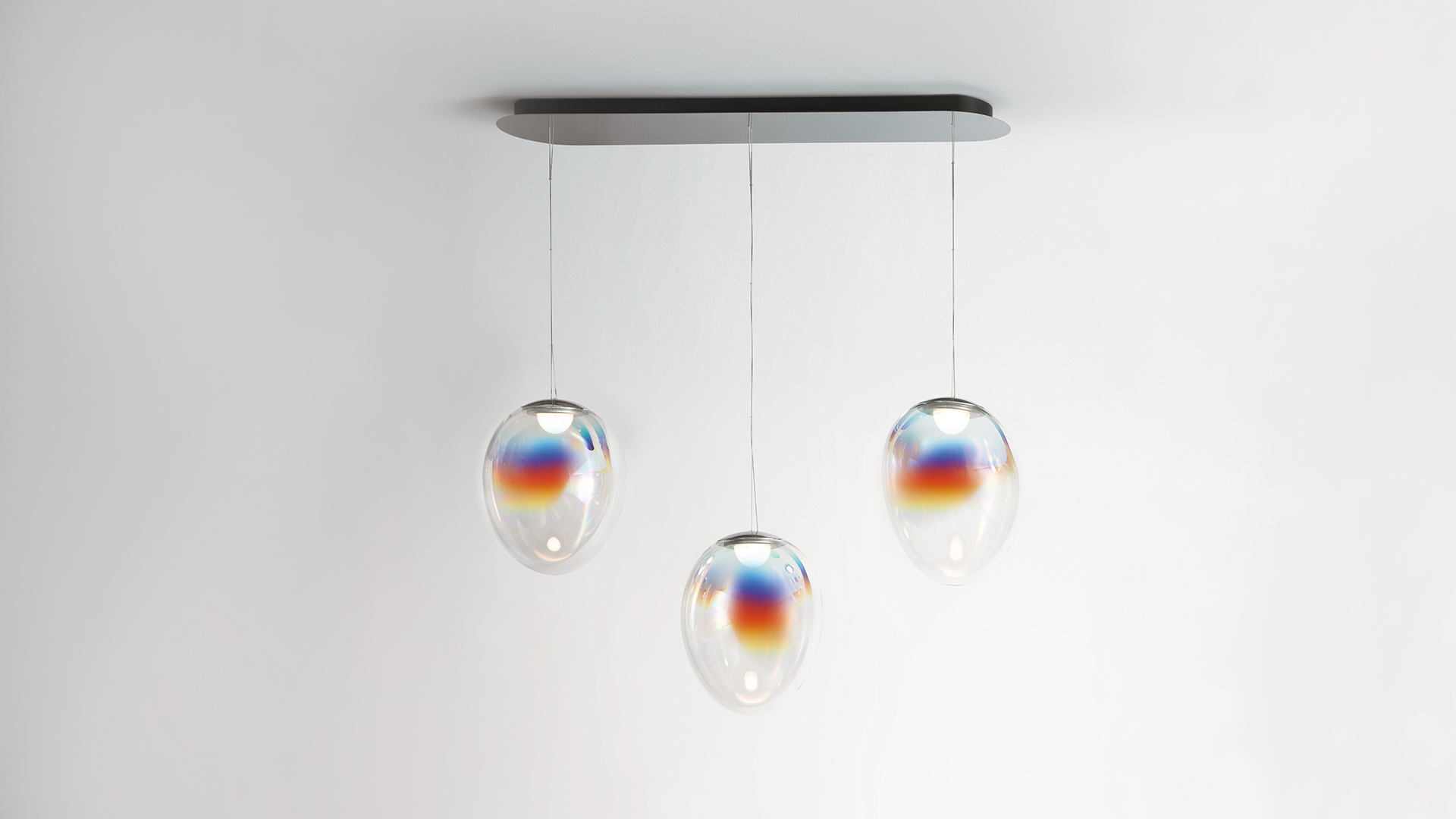 Stellar Nebula table lamp: iridescent egg-shaped glass diffuser with rainbow reflections on gold base, teal background