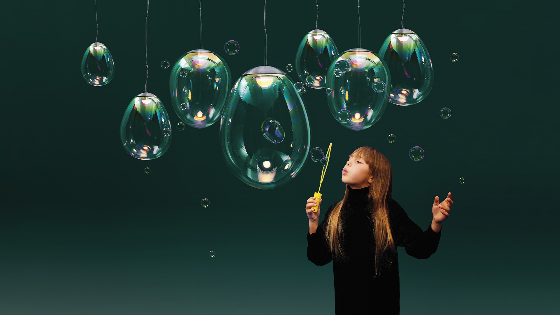 Two Artemide Stellar Nebula pendant lamps with iridescent blown glass shades displaying colorful internal reflections, hung against a white wall