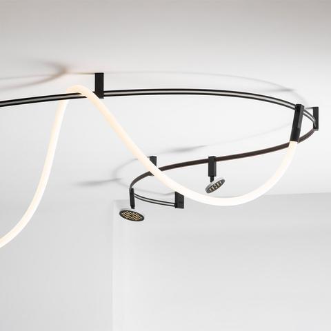 Artemide Sylt ceiling lamp: dark metal curved rail with glowing white LED strip and two adjustable spotlights mounted on ceiling