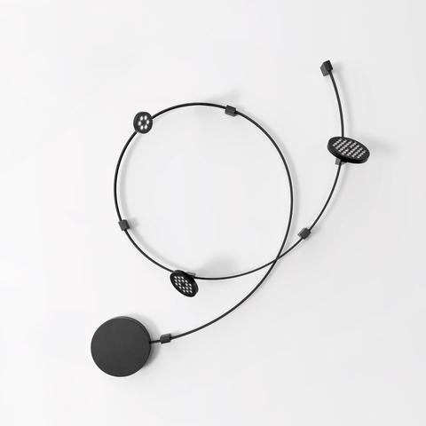 Artemide Sylt Stand Alone: black circular cable system with one solid disc and two perforated oval LED modules on white background