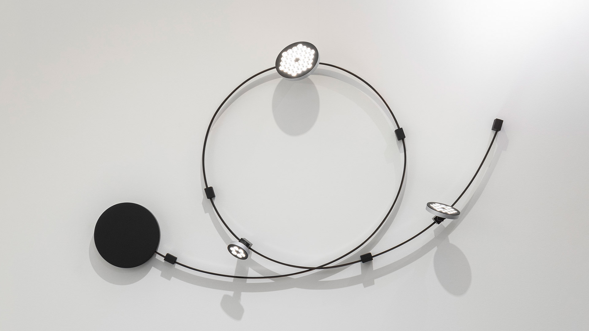 Artemide Sylt system: modular black track lighting with pendant bulbs, circular and curved configurations on ceiling and wall