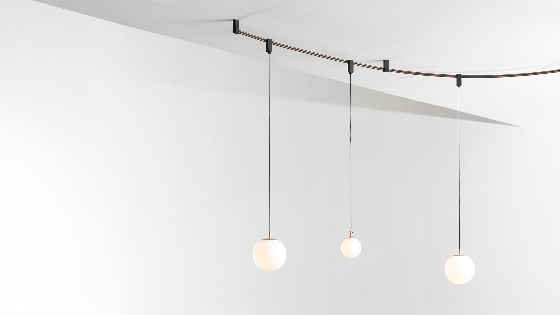 Two black Artemide Sylt adjustable cylindrical spotlights mounted on a flexible cable track system, emitting warm white light