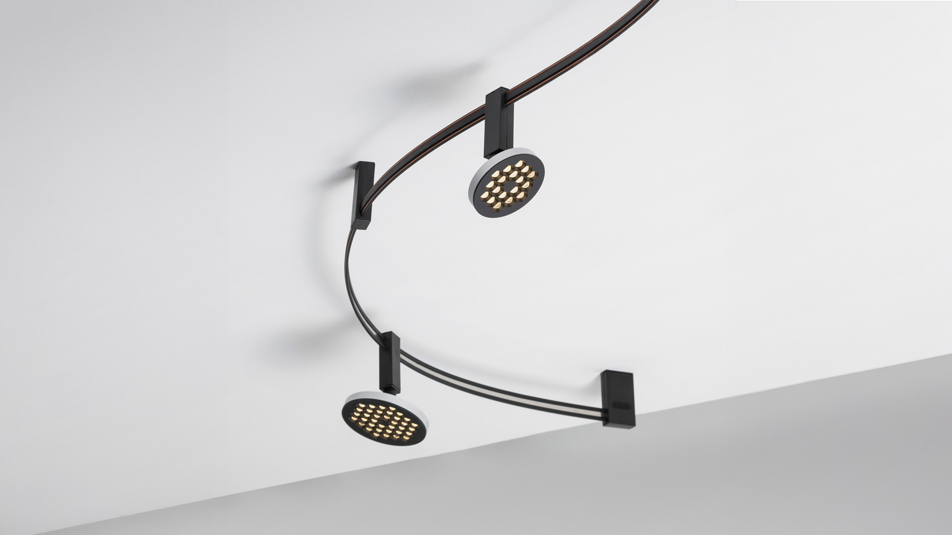 Artemide Sylt track lighting: matte black linear LED pendant suspended from a ceiling rail via a rectangular bracket