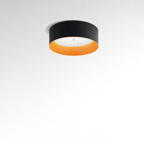 Artemide Tagora Soffitto 570 ceiling lamp: cylindrical black exterior, warm orange interior, with diffused downward LED light.