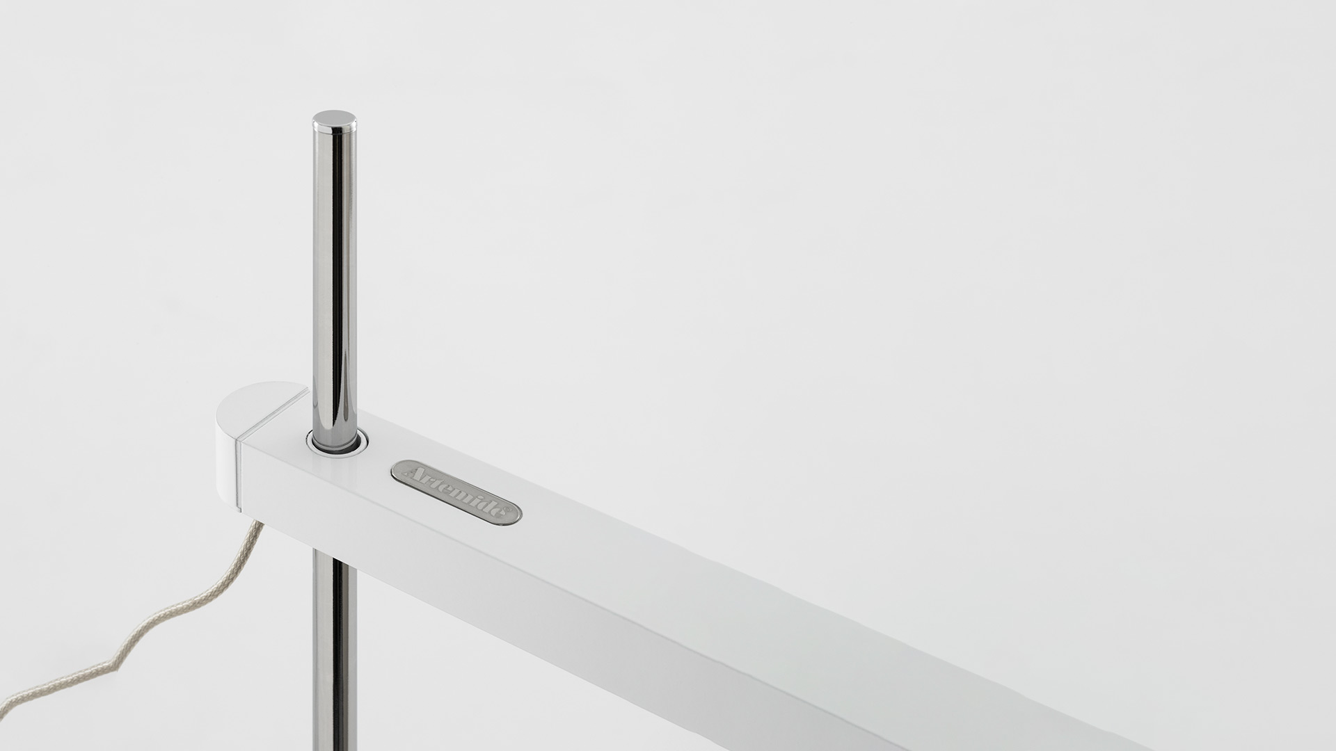 Close-up of Artemide Talak Professional Table lamp: white horizontal arm with control button and chrome vertical stem detail