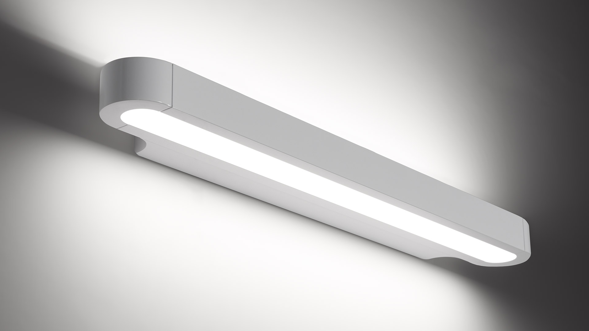 Artemide Talo wall lamp: sleek horizontal LED bar in white aluminum, emitting warm diffused light downward and upward glow on wall