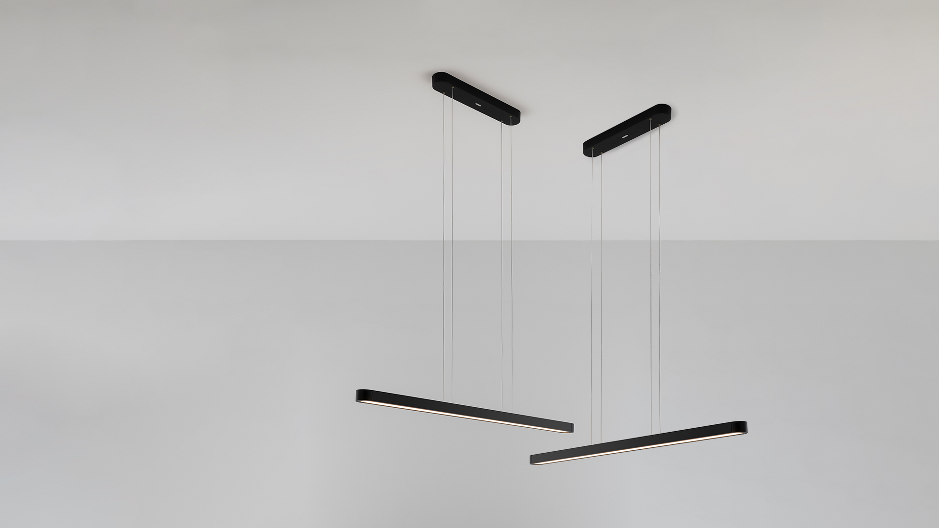 Talo suspension pendant lamp by Artemide: elongated black linear LED fixture with warm white diffuser, suspended by thin cables
