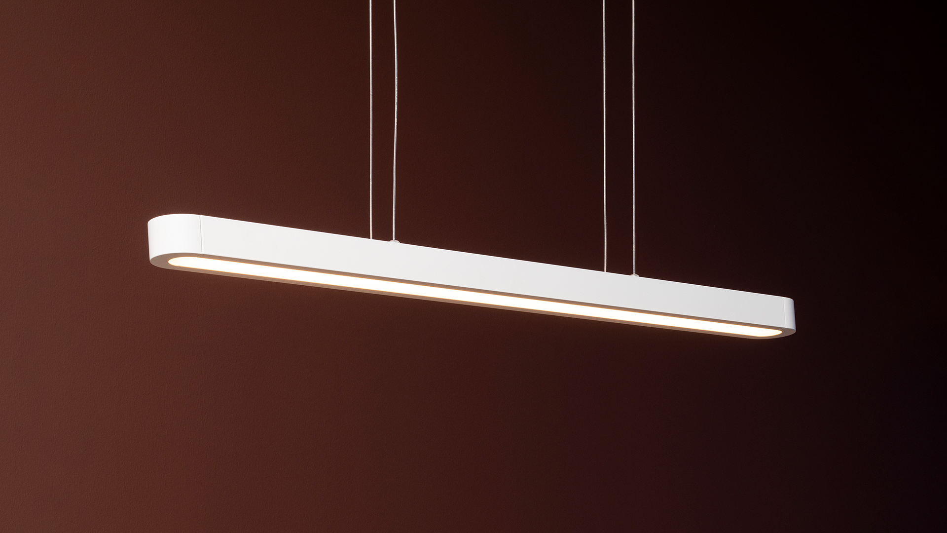 Talo suspension lamps by Artemide: three slim black linear LED pendants hanging at varying heights on thin cables