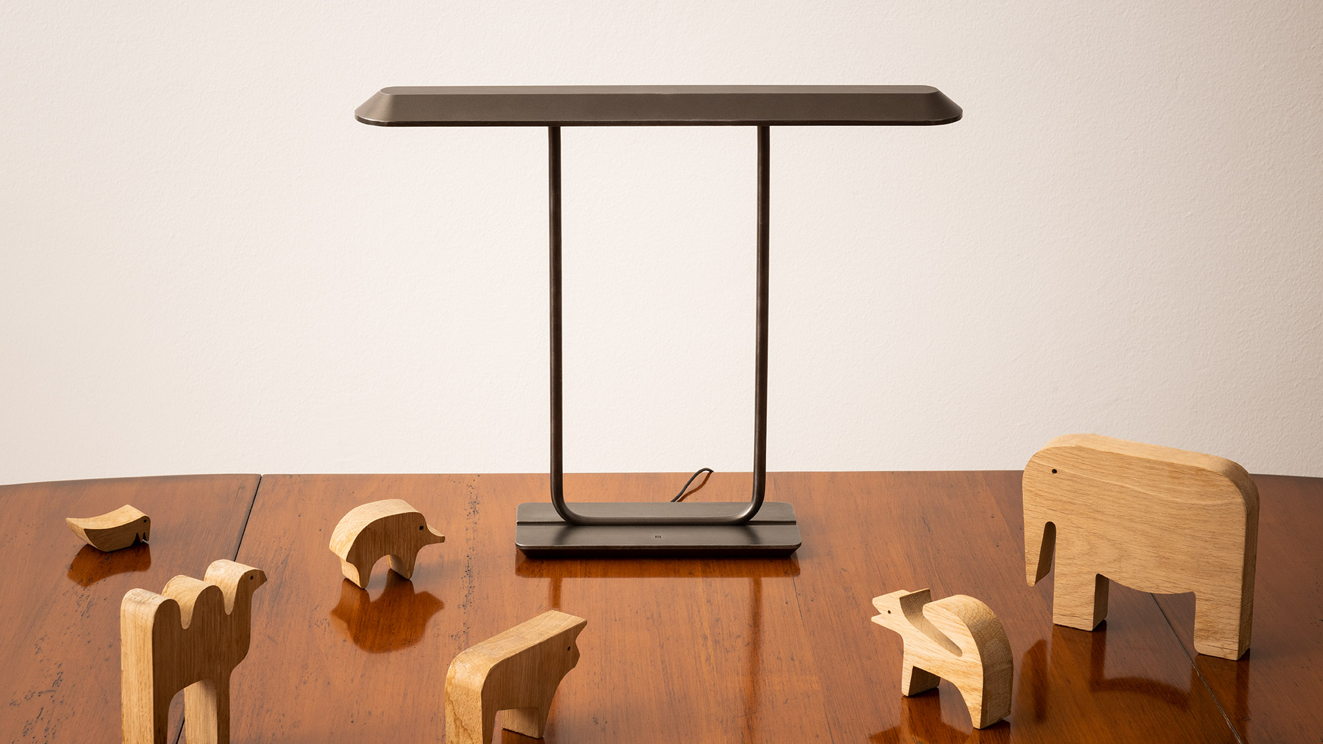 Artemide Tempio table lamp with dark rectangular shade on slim black frame, displayed on a mid-century wooden sideboard with decorative vase