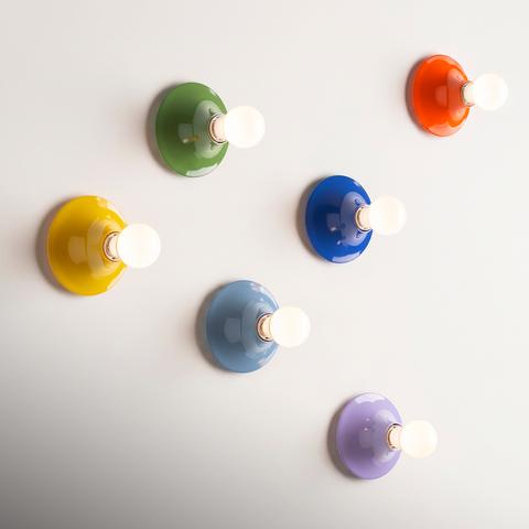 Six Artemide Teti wall sconces in glossy colors: yellow, green, blue, light blue, orange, and lavender, each with an exposed bulb
