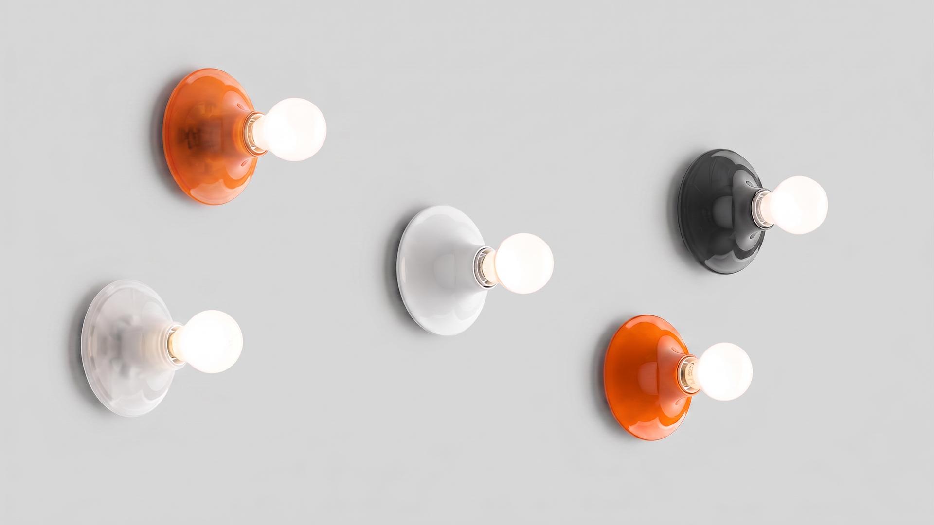 Two Artemide Teti wall lamps mounted on white wall: one yellow and one green ceramic disc base, each with exposed globe bulb