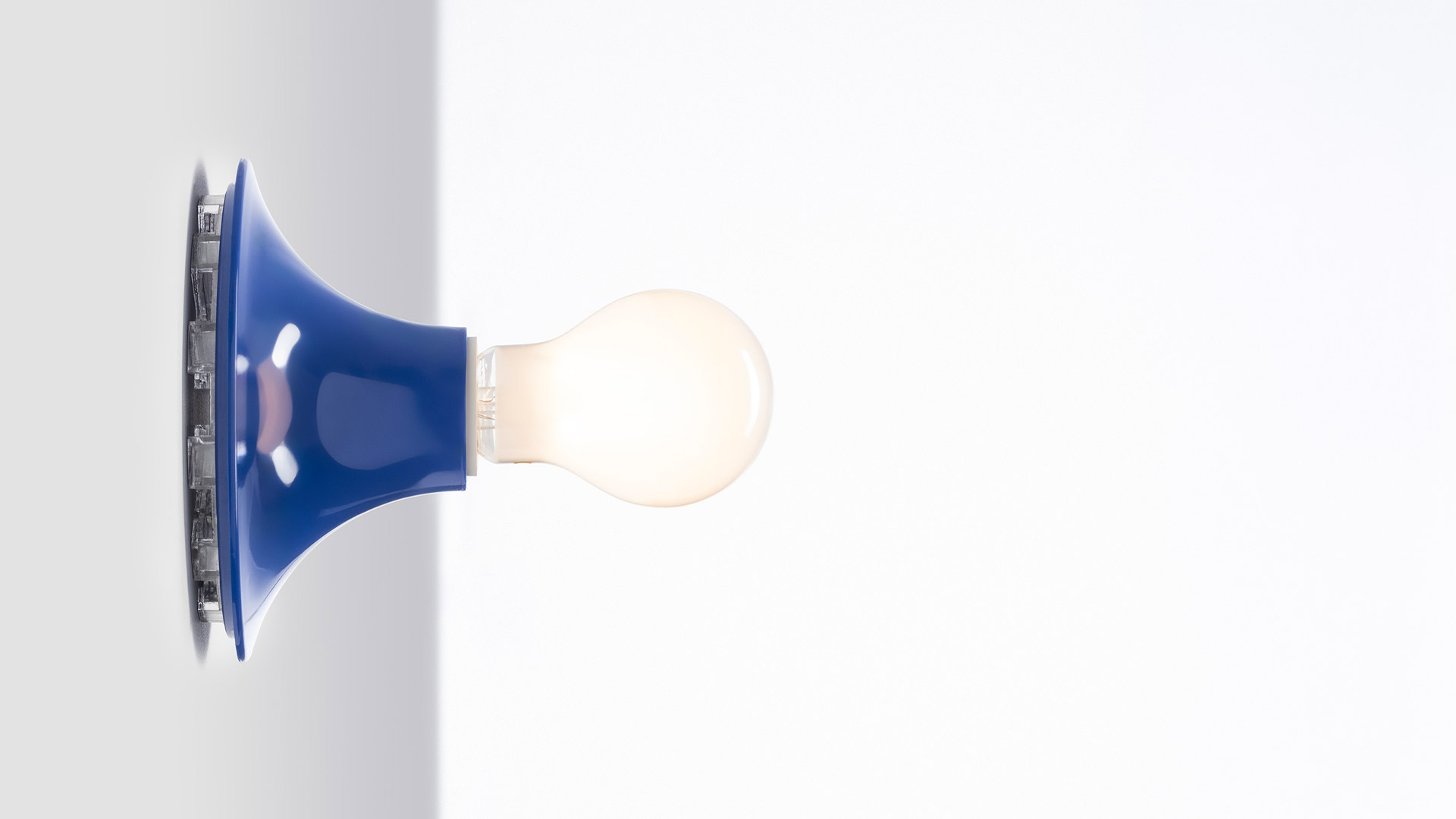 Artemide Teti collection in deep red: wall lamp with circular disc shape alongside table lamps, floor lamp, and accessories