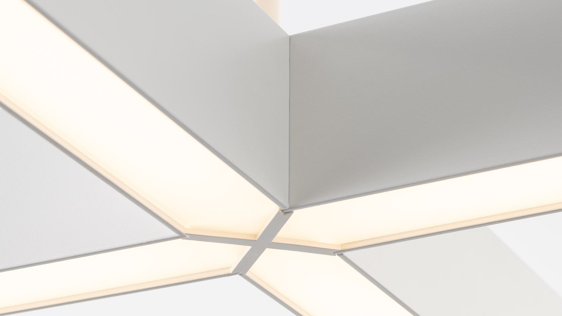 Artemide Tetras modular ceiling light system: silver aluminum profiles forming a cross shape with dark honeycomb anti-glare LED diffusers