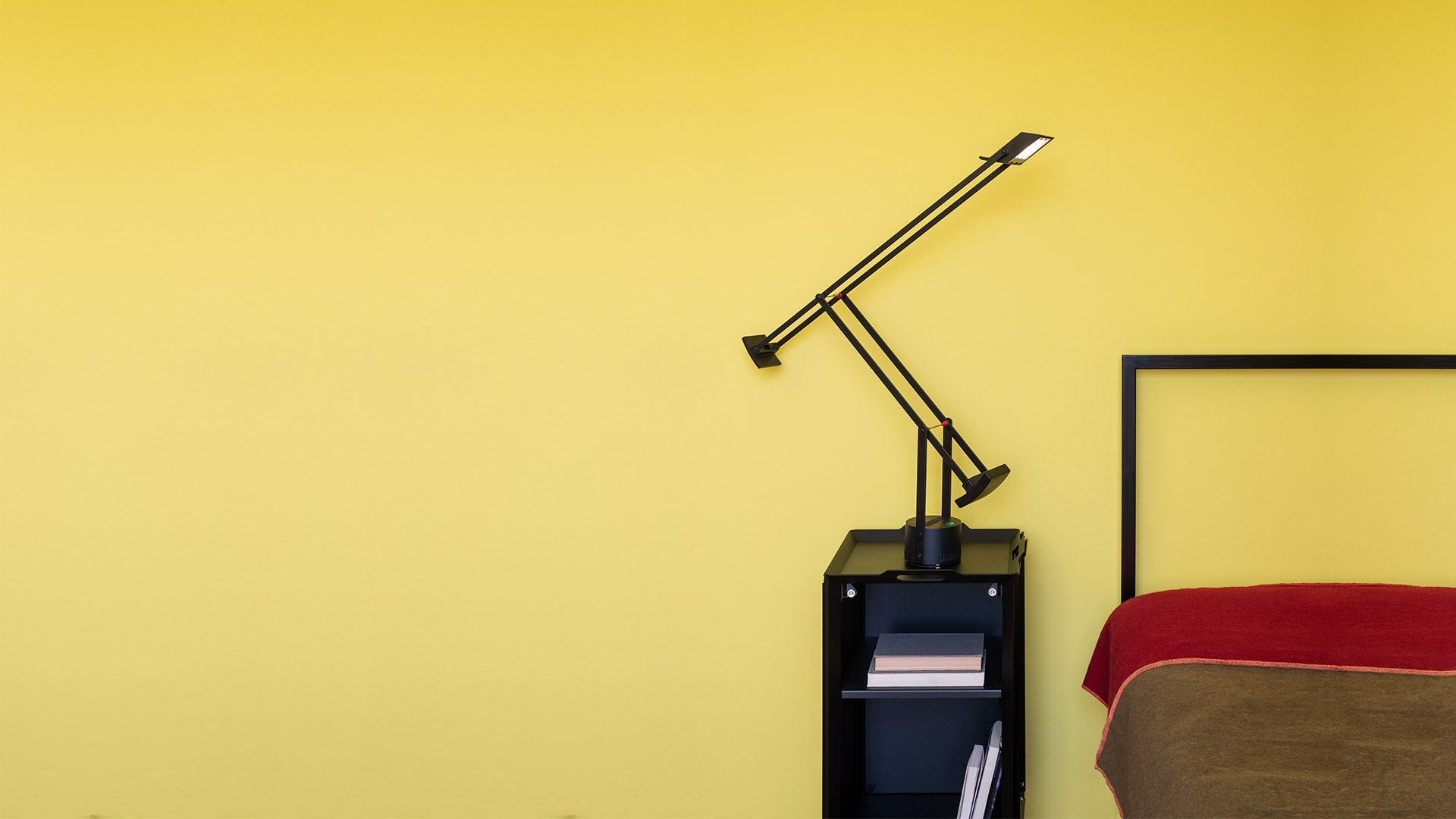 Three Artemide Tizio desk lamps in black, white, and dark gray, showcasing their iconic counterbalanced articulated arm design.