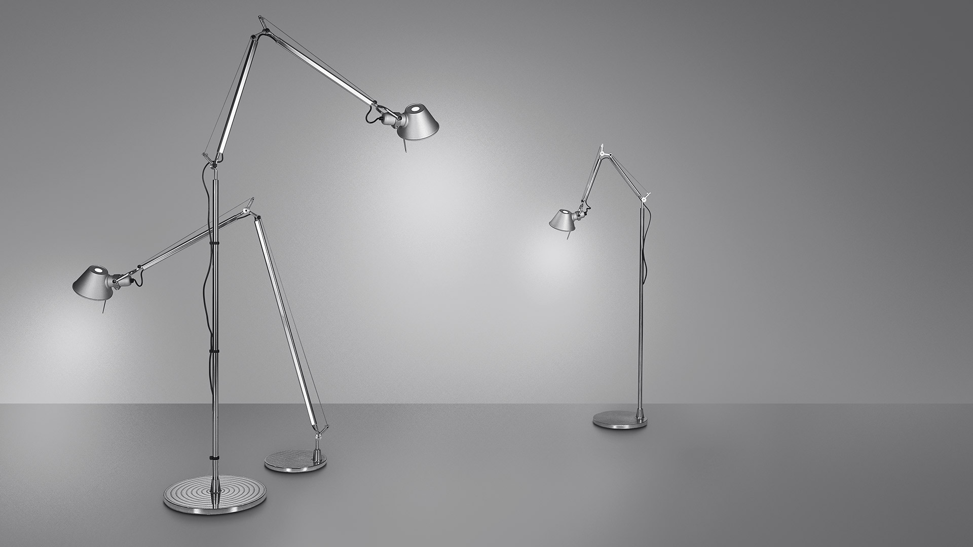 Two Artemide Tolomeo floor lamps in polished aluminum: large Tolomeo Floor with extended arm on left, compact Tolomeo Micro Terra on right
