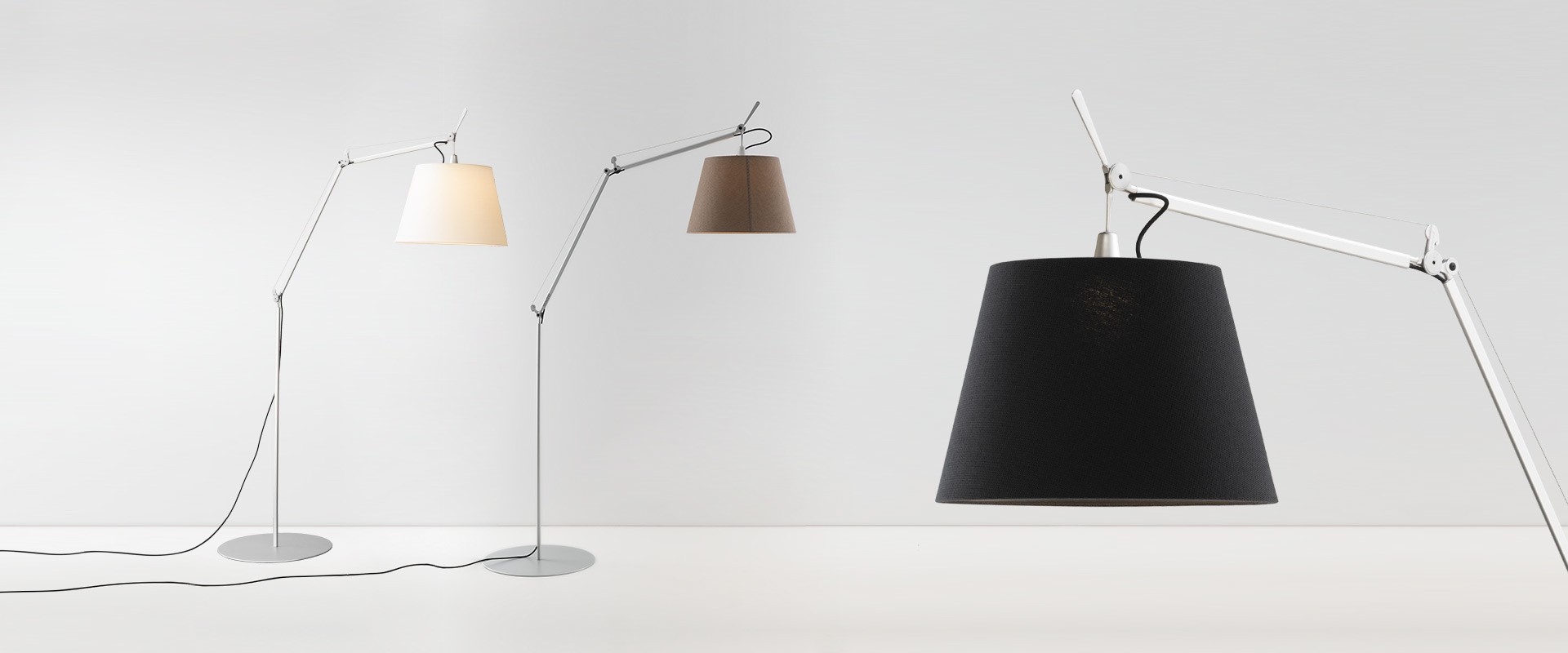 Three Artemide Tolomeo Paralume Outdoor floor lamps with adjustable arms and conical shades in white, brown, and black