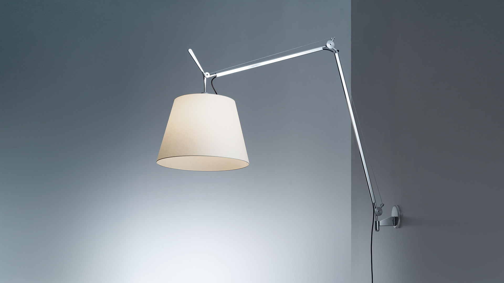 Artemide Tolomeo Mega Parete wall lamp with adjustable aluminum arm and large conical parchment shade, mounted on grey wall