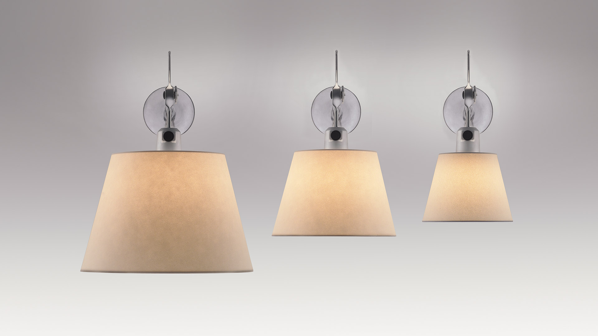 Three Artemide Tolomeo Parete wall lamps with beige parchment shades and chrome wall mounts, shown in three sizes