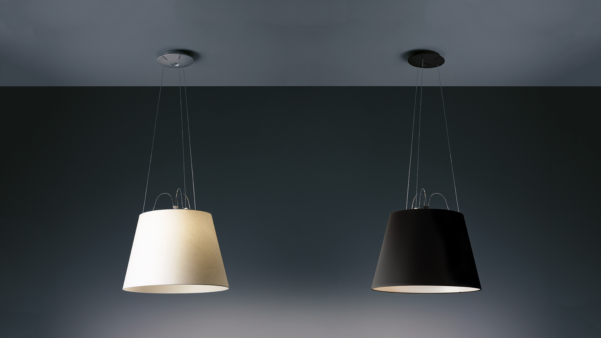 Two Artemide Tolomeo Mega Sospensione pendant lamps: left ivory white conical shade, right matte black conical shade, suspended by thin cables